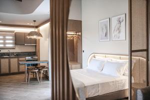 a bedroom with a bed and a kitchen with a table at Terra Hélios Suites & Studios in Kyparissia
