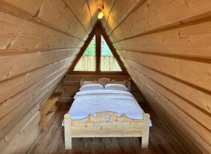 uma cama num chalé de madeira com uma janela em JEDYNOCKA em Kościelisko