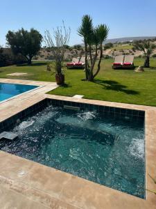 een zwembad in een achtertuin met een gazon en bomen bij Luxueuze villa Taghazout Bay in Taghazout