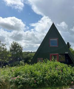 a green house with a red window on the side of it at Nice holiday home in beautiful resort in Farsø