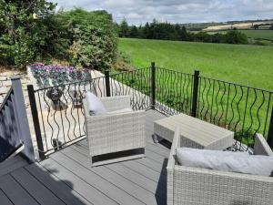 two chairs and a table on a deck with a fence at Hillview Haven at Hillcrest in Liskeard