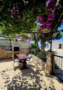 a table and a chair under a tree with flowers at Small House Postup in Orebić