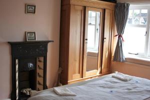 a bedroom with a bed and a fireplace and a window at Traditional New Forest cottage in Brockenhurst. in Brockenhurst