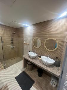 La salle de bains est pourvue de 2 lavabos, d'une douche et de miroirs. dans l'établissement Villa contemporaine, à Marrakech