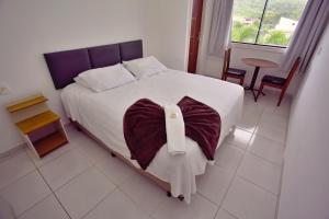 een slaapkamer met een groot bed met een kussen erop bij Pousada Paulett's - Hospedagem na Zona Norte de Ilhéus - Bahia in Ilhéus