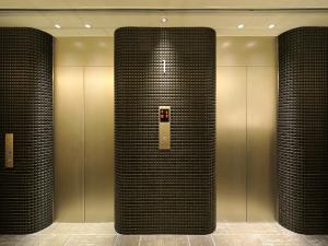 a lobby with two elevators with black tile columns at Hakata Green Hotel Annex in Fukuoka