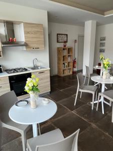 eine Küche mit 2 Tischen, weißen Stühlen und einer Theke in der Unterkunft Percebes Exclusive B&B in Cutrofiano