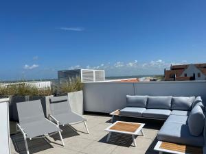 a patio with a couch and chairs on a roof at Penthouse in Badhuis Cadzand in Cadzand