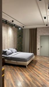 a bedroom with a large bed and a wooden floor at Park Vurğun Residance Loft Designer in Baku