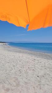 um guarda-sol laranja numa praia arenosa com o oceano em L'ISOLA DEI VACANZIERI em SantʼAndrea Apostolo dello Ionio