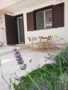 a patio with a table and chairs and purple flowers at Aura Apartments - Orizzonte Turismo in Porto Cesareo
