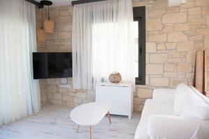 a living room with white furniture and a stone wall at Pietra Mare Villas in Polychrono