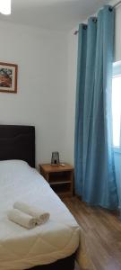 1 dormitorio con 1 cama y una ventana con cortinas azules en Lagoas, en Tavira