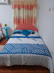a bed with a blue and white comforter in a room at Casa Hostal Perla Roja in Ríohacha