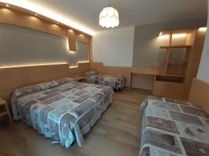 a room with two beds and a table in it at Hotel Garnì Miramonti in Falcade