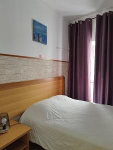 1 dormitorio con cama, mesa y ventana en Lagoas, en Tavira