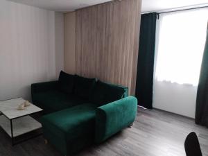ein Wohnzimmer mit einem grünen Sofa und einem Tisch in der Unterkunft Apartmán pri parku in Solčany