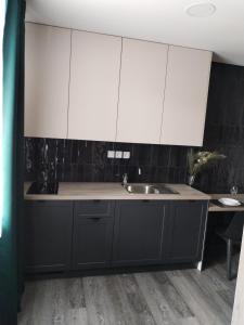a kitchen with black and white cabinets and a sink at Apartmán pri parku in Solčany