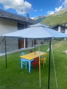 una mesa amarilla con sillas bajo una sombrilla azul en Casa Vauterin VDA CIR 0019- 0021-0022-0026-, en La Thuile