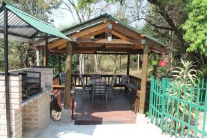 une pergola en bois avec une table et des chaises sur une terrasse dans l'établissement Bush Lilly Cottage, à Hazyview