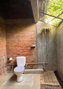 uma casa de banho com um WC ao lado de uma parede de tijolos em Nongu Home em Triquinimale