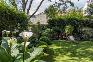 a garden with a white flower and a chair at Escale Rochelaise B&B, SPA bain nordique et sauna tonneau in La Rochelle