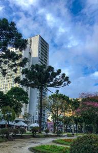 un grand bâtiment blanc avec des arbres devant dans l'établissement Apto central, com vista deslumbrante!, à Curitiba