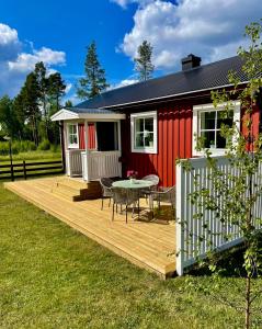 a house with a deck and a table in front of it at Litet hus på landet 