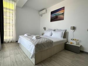 ein weißes Schlafzimmer mit einem großen Bett mit weißen Kissen in der Unterkunft Alfie Mamaia Nord in Mamaia Nord – Năvodari