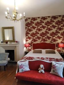 a teddy bear sitting on a red couch in a bedroom at Le Logis de Saint Cyr in Issoudun