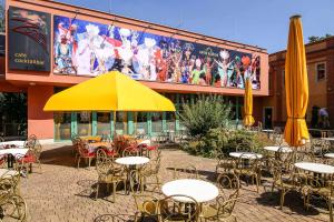 un patio al aire libre con mesas, sillas y una sombrilla amarilla en Backstage Hotel en Dresden