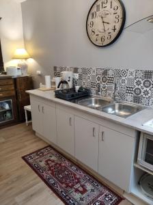 a kitchen with a sink and a clock on the wall at Le Logis de Saint Cyr in Issoudun