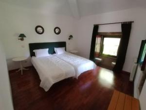 a bedroom with a white bed and a wooden floor at Casa das Feitorias Douro Valley in Baião