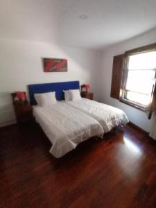 Schlafzimmer mit einem großen weißen Bett mit blauem Kopfteil in der Unterkunft Casa das Feitorias Douro Valley in Baião
