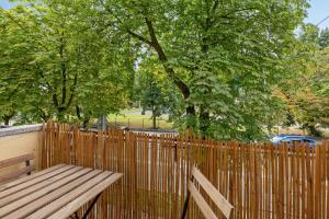 eine Holzbank neben einem Zaun mit Bäumen in der Unterkunft Pokoje Gdynia Witomińska in Gdynia