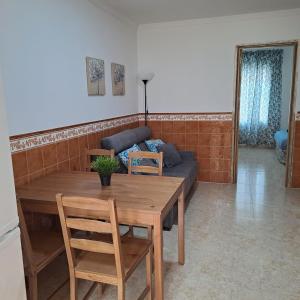 ein Wohnzimmer mit einem Holztisch und einem Sofa in der Unterkunft Apt. cerca de la playa y airport in Málaga