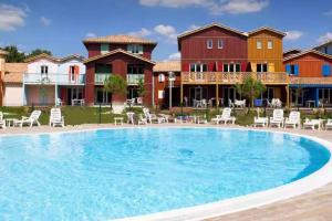 a large swimming pool in front of some houses at Le Nid du Teich in Le Teich