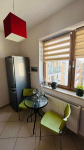 a kitchen with a table and green chairs and a refrigerator at Warszawa Bemowo Pokoje in Warsaw