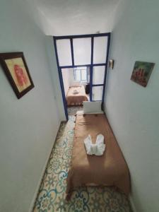 Habitación pequeña con cama y ordenador portátil. en Riad AYLAL en Essaouira