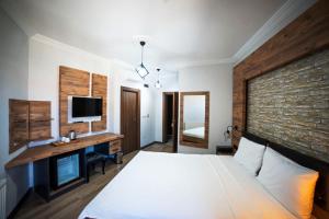 a bedroom with a bed and a desk with a television at İmroz Adali's Butik Otel in Gokceada Town