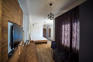 İmroz Adali's Butik Otel في غوكجيادا: غرفة معيشة فيها تلفزيون وسرير في غرفة