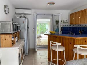 een keuken met een koelkast en een aanrecht met krukken bij Bel Appartement avec Jardin pour 4 Personnes Climatisé avec Accès plage de la Gorguette à pied in Sanary-sur-Mer