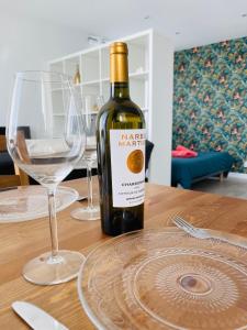 una botella de vino sentada en una mesa con dos copas en La Pampa - Blow Résidences, en Loudéac