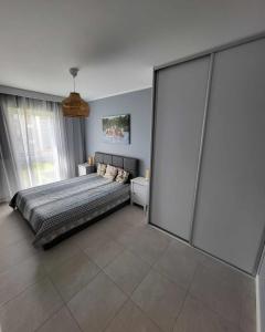 a bedroom with a bed and a large glass wall at Apartament Turkusowy in Międzywodzie