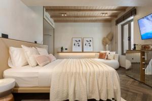 a bedroom with a large white bed and a television at Agave Boutique Hotel in Laganas