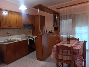 una cucina con armadi in legno e un tavolo con una tovaglia di Irini apartment 3 a Néa Koútali