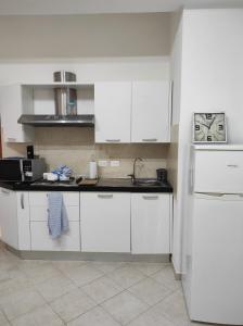 a white kitchen with a sink and a refrigerator at Casa Lore in Livorno