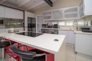 a kitchen with a white counter and chairs in it at LIFESTYLE LIVING in Cape Town