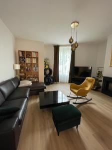 ein Wohnzimmer mit einer schwarzen Couch und einem Sessel in der Unterkunft maison 15 mins du Mans in La Suze-sur-Sarthe