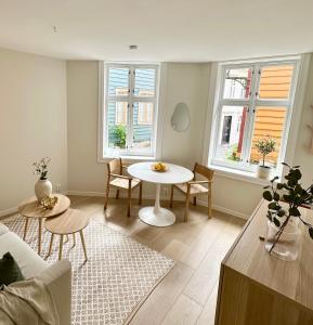 a living room with a table and two windows at Knøsesmauet Apartment in Bergen